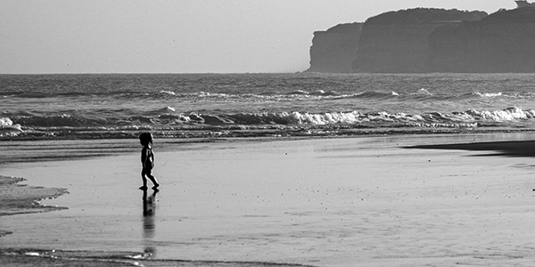 Fotografia en blanco y negro, de un niño parado frente al mar