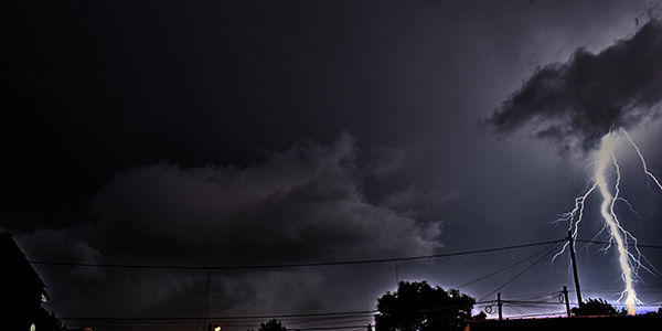 Fotografia de un relampago cayendo en una zona urbana de noche